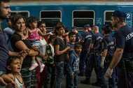 A migrant family faced police officers at the Keleti train station in Budapest, which was shut down temporarily Tuesday under the strain of the influx.